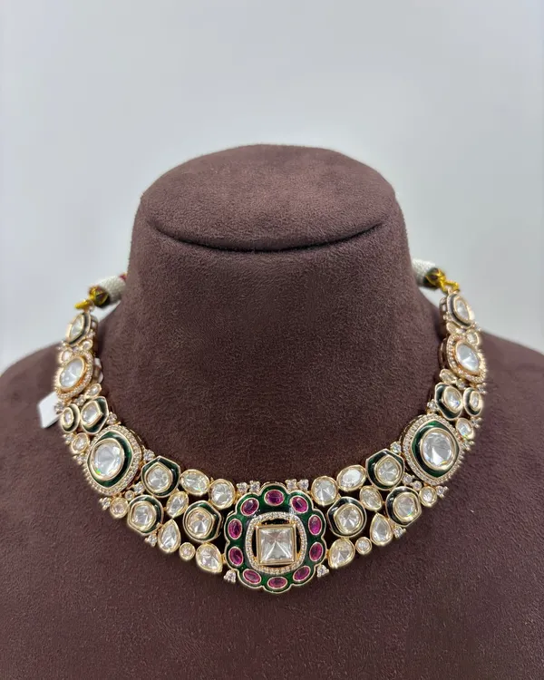 A classic kundan choker necklace with large uncut polki stones, accented with a ruby and emerald center motif. This is a versatile piece for weddings and festive events.
