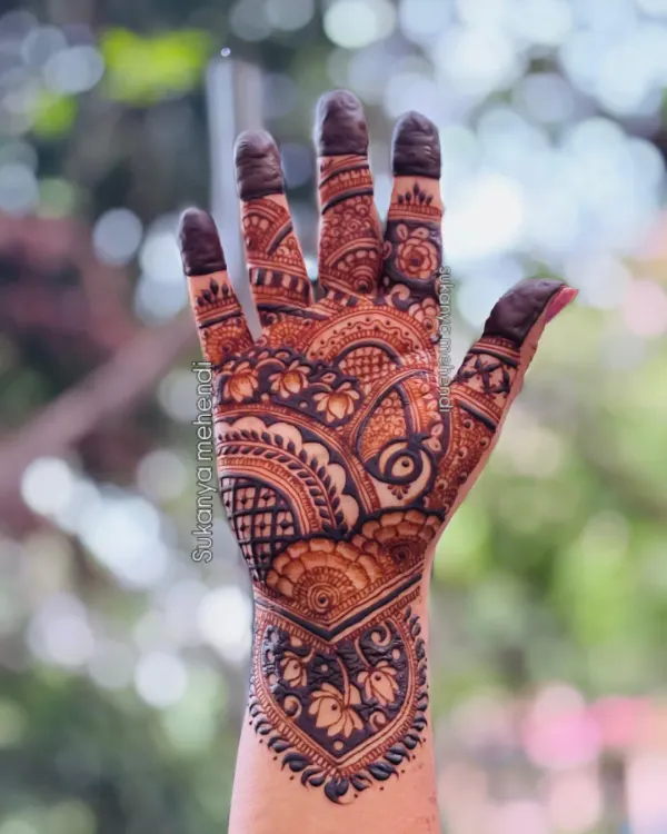 A stunningly detailed, full-palm traditional mehendi design. The combination of lotus flowers, semi-circles, and fine lines creates a rich and captivating pattern.