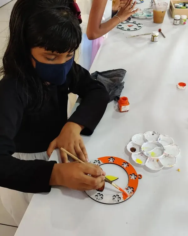A young artist painting a beautiful Diwali hanging during a festive birthday party. It's a great way to celebrate and create holiday decor.