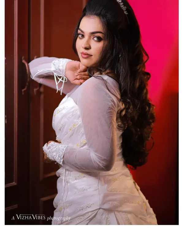 A full-length shot of a bride in her beautiful white wedding gown. The makeup is classic and elegant, with a voluminous hairstyle that adds a touch of glamour.