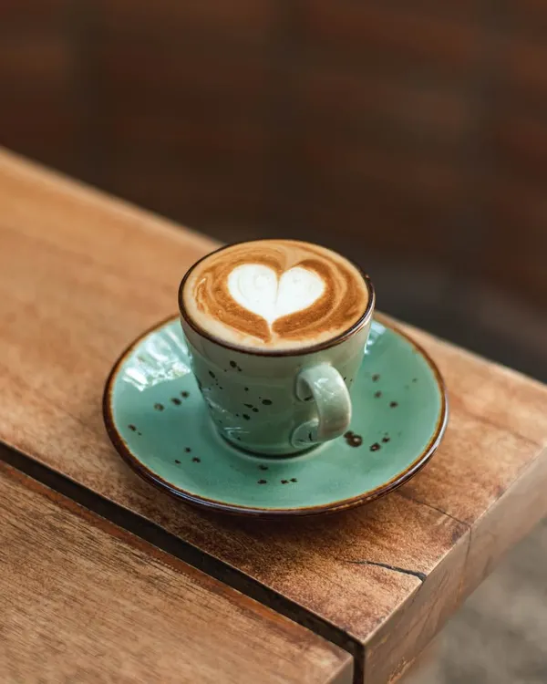 A perfectly poured cappuccino with a heart-shaped latte art, served in one of our signature ceramic cups. It's a cup of love to start your day.
