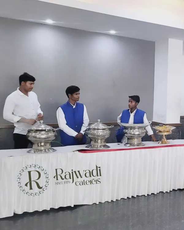 My team ready for service behind a professionally set table featuring my brand logo. The clean white table skirting and silver chafing dishes are part of my standard setup.