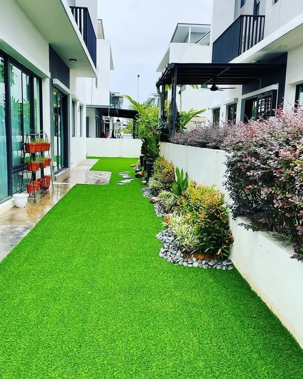A narrow side yard transformed with vibrant artificial turf. We paired the turf with a raised garden bed filled with a mix of shrubs and plants, creating a beautiful and completely hassle-free green space between two homes.