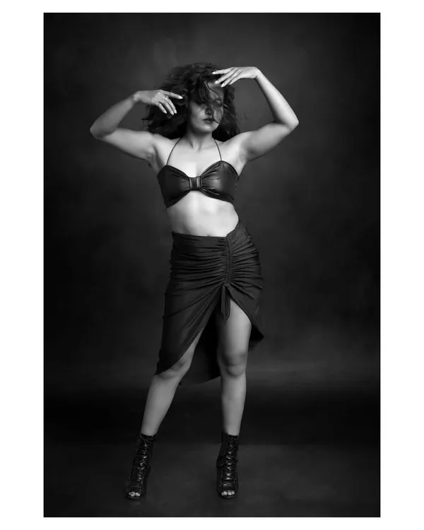 A powerful black and white portrait of a dancer. The pose is full of tension and energy, and the dramatic lighting highlights the strength and definition of her muscles.