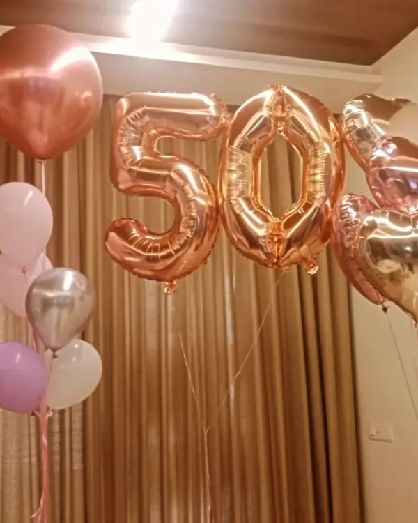 Celebrating a golden jubilee with style. This simple yet elegant setup for a 50th birthday features rose gold number balloons and coordinating heart and orbz balloons.