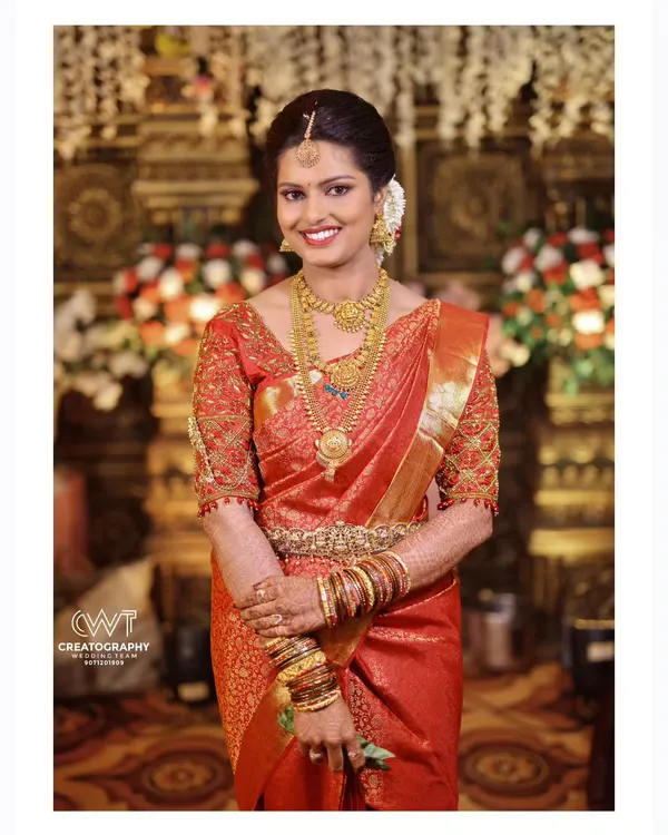 An elegant bridal portrait showcasing a bride in a classic red Kanjeevaram saree, adorned with beautiful temple jewelry.