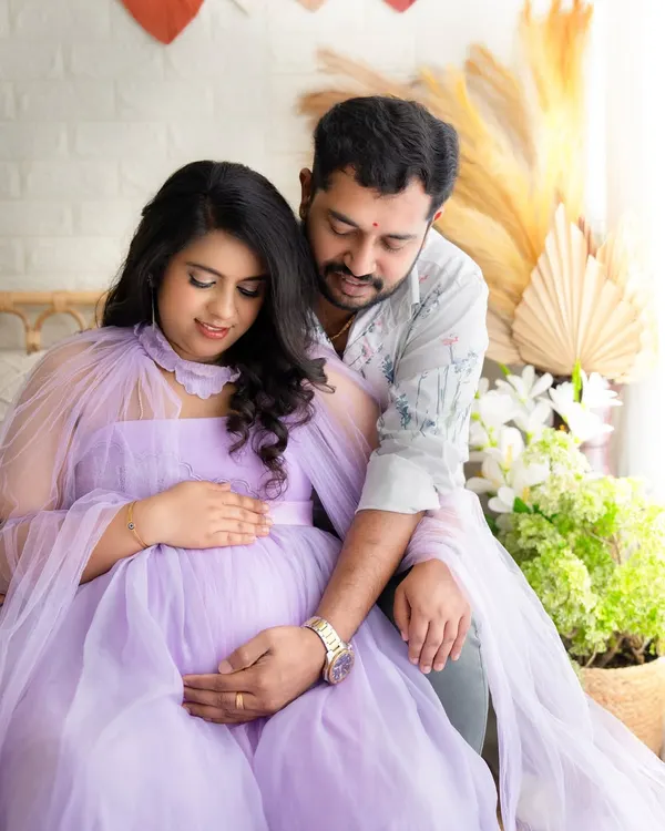 An intimate moment between an expecting couple. They are both looking down at the baby bump, their hands gently placed on it, showing their shared love.