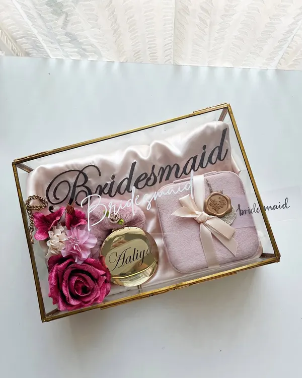 This is how you ask your best friends to stand by your side. Our signature glass and brass box is curated with a personalized satin robe, a velvet jewelry case, and a custom engraved pocket mirror, creating a bridesmaid proposal that feels truly luxurious and personal.