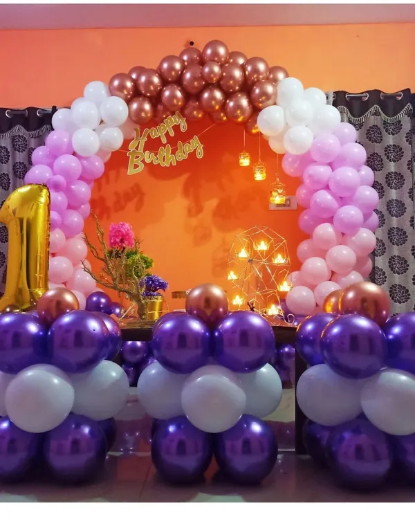 A beautiful and compact first birthday setup perfect for a living room. This decoration features a circular balloon arch in purple, pink, and rose gold, with a large foil '1' balloon to mark the special occasion.