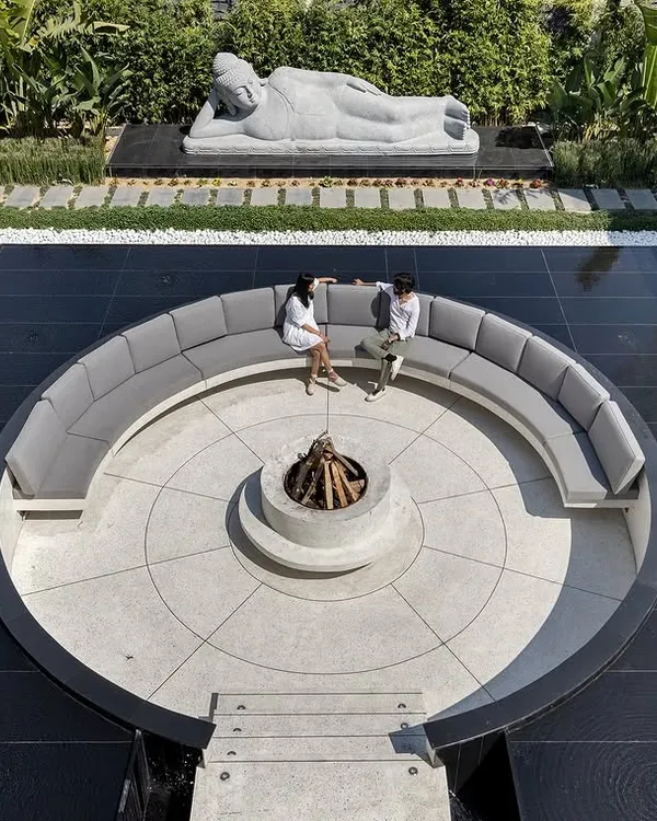 An aerial day view reveals the perfect geometry of this outdoor sanctuary. The circular sunken lounge with its central fire pit is perfectly centered within a square water body, creating a powerful sense of balance and order. The design provides a space for connection, surrounded by water and greenery.