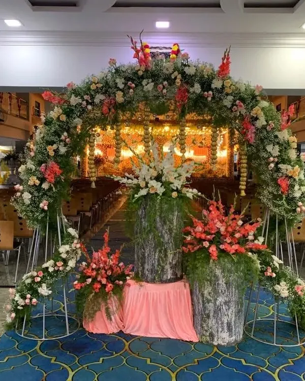 A grand floral archway I created for a naming ceremony held in a large hall. The entrance is decorated with a mix of fresh flowers and greenery, leading to the main event space.