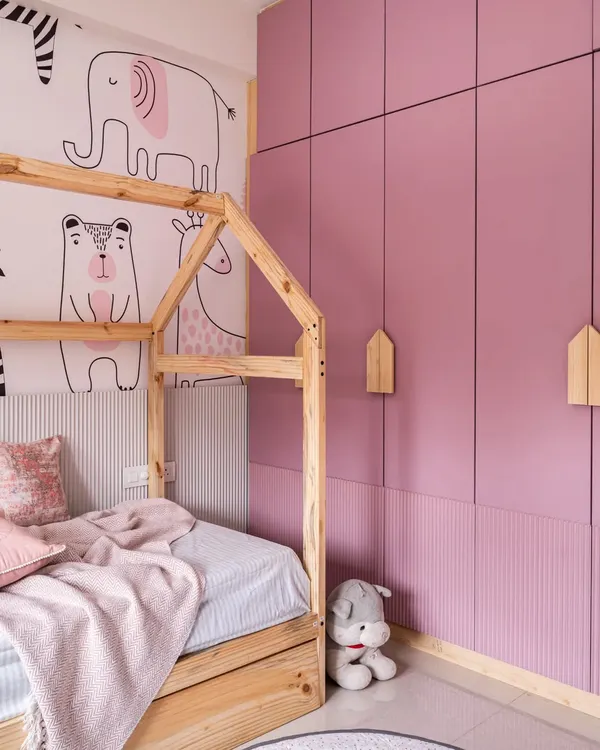 For this shared girls' bedroom, the main request was a pink color scheme and ample storage. To solve the challenge of a compact space, I used a trundle bed that folds away, making room for a study area. The house-frame bed and animal-themed wallpaper add a playful touch.