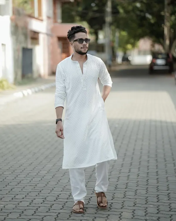 A classic men's fashion portrait. The subject's confident walk down a quiet street, dressed in a crisp white kurta, creates a timeless and stylish look.