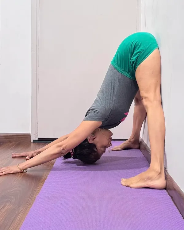 Prasarita Padottanasana (Wide-Legged Standing Forward Bend) at the wall. One has to find the median line of each asana so that energy is properly distributed. The horizontal is the present, where the future and past meet.