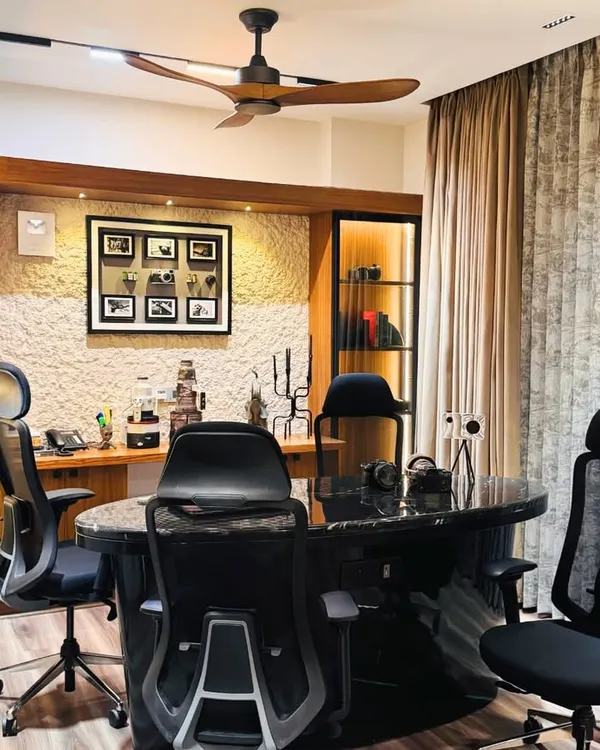 A sophisticated home office designed for productivity, featuring a large marble-top desk, ergonomic chairs, and custom wood cabinetry with integrated lighting for a professional yet warm environment.