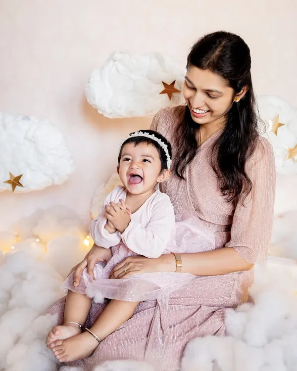 A dreamy "above the clouds" setup for a first birthday photoshoot. This mother and daughter moment is so sweet, surrounded by soft clouds and twinkling stars, all created in the comfort of their home.