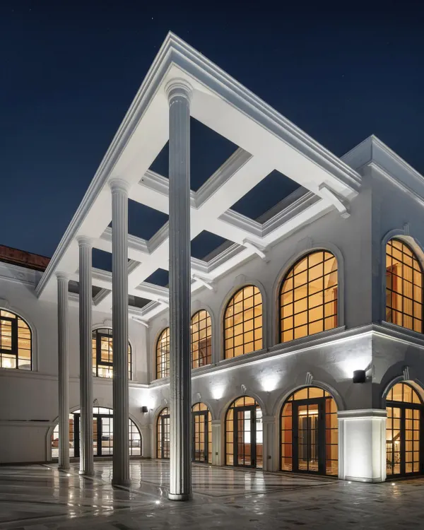 The Wanderlust Villa at night, where the grand classical facade with its towering columns and arched windows is beautifully illuminated. The design creates a powerful statement of timeless elegance.