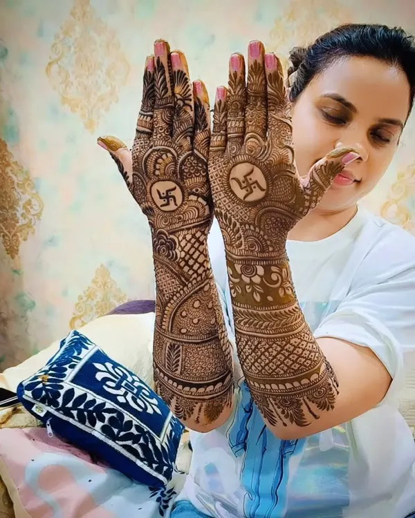 A happy client proudly displaying her traditional mehandi with Swastika symbols. Her smile says it all.