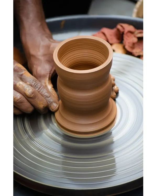 A close up of a pot being expertly shaped on the wheel. This image captures the satisfying process of turning a simple lump of clay into a beautifully formed vessel.