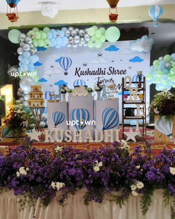 An "Up, Up and Away" hot air balloon theme for a first birthday, using a soft blue and green color palette.