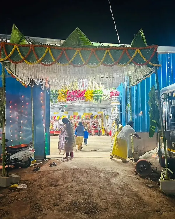 A traditional 'chapra' or woven leaf canopy, decorated with marigold garlands, set up at the entrance for a temple festival, creating a rustic and authentic welcome.