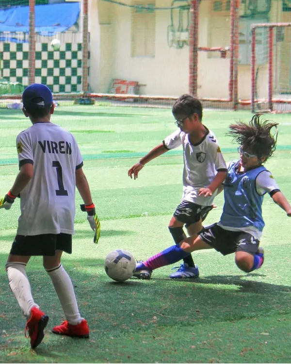 A player makes a decisive slide tackle during a competitive match, showcasing the courage and timing we instill in our defenders.