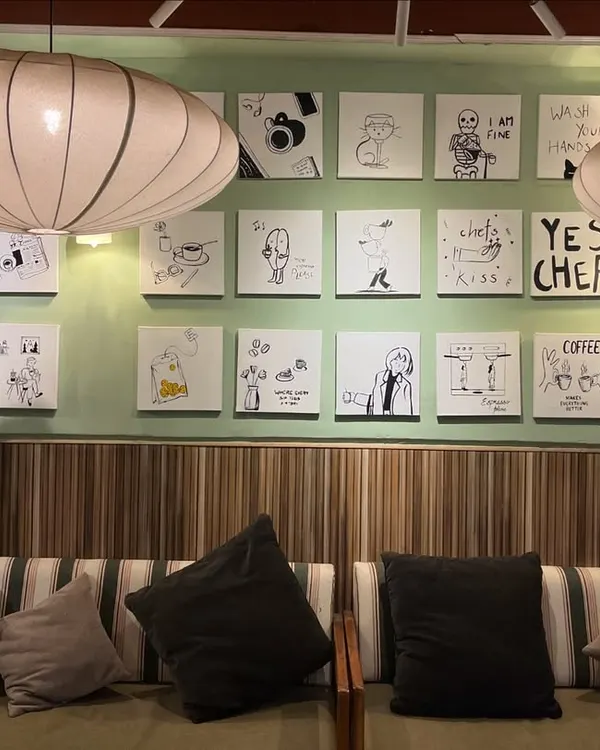 A full view of the gallery wall I created for Sidewalk Cafe in Kanpur. This set of 24 custom doodle-style paintings adds a fun and quirky character to the space.