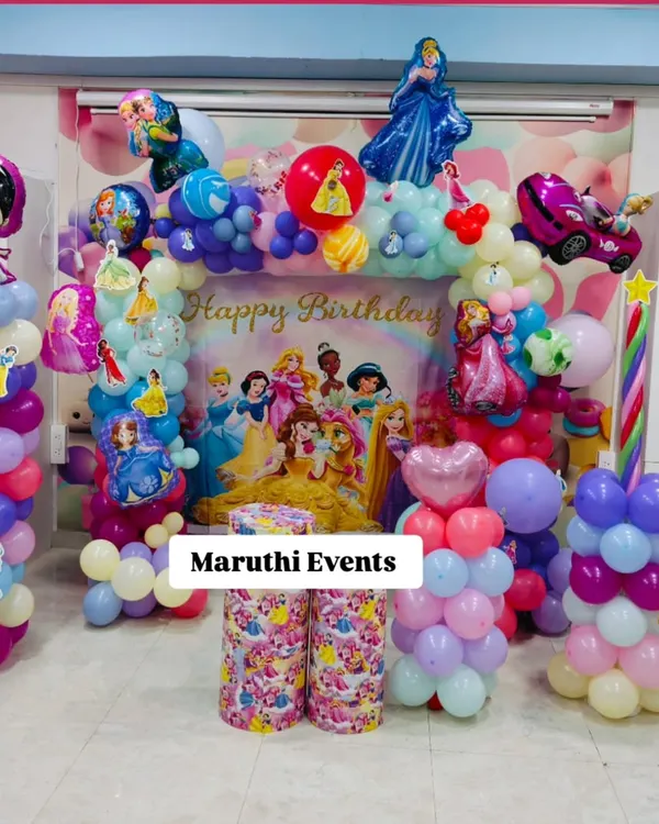 A magical Disney Princess birthday party. This setup includes a large backdrop featuring all the princesses, a colorful balloon arch, and character foil balloons of Sleeping Beauty and Masha.