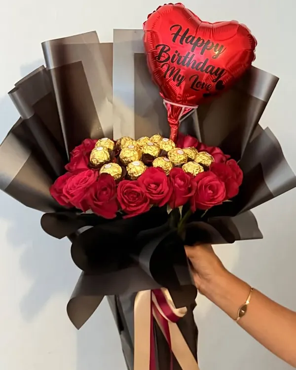 Making birthdays more special with this stunning hand-held bouquet. It features deep red roses and Ferrero Rocher chocolates, wrapped in sophisticated black and grey paper and topped with a "Happy Birthday My Love" balloon.