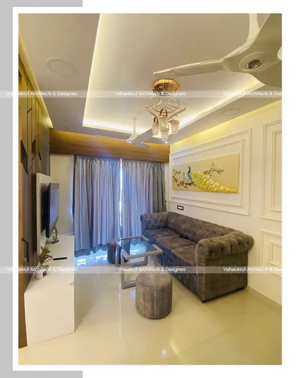 A view of a completed living room in Dronagiri, Uran. The design features a comfortable tufted sofa, elegant wall molding, and a striking 3D peacock wall art piece that serves as a focal point.