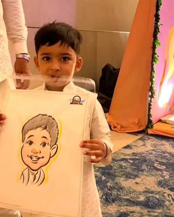 A young boy in a kurta holds his caricature at a family function. My drawings are always a huge hit with the kids.