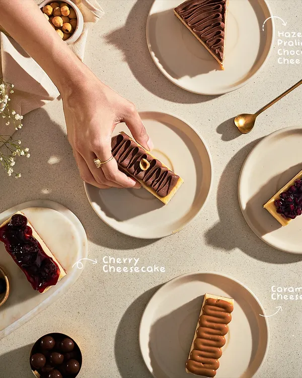 Decisions, decisions. An overhead shot of my cheesecake selection, including Hazelnut Praline, Cherry, and Caramel cheesecakes, inviting you to pick your favorite.