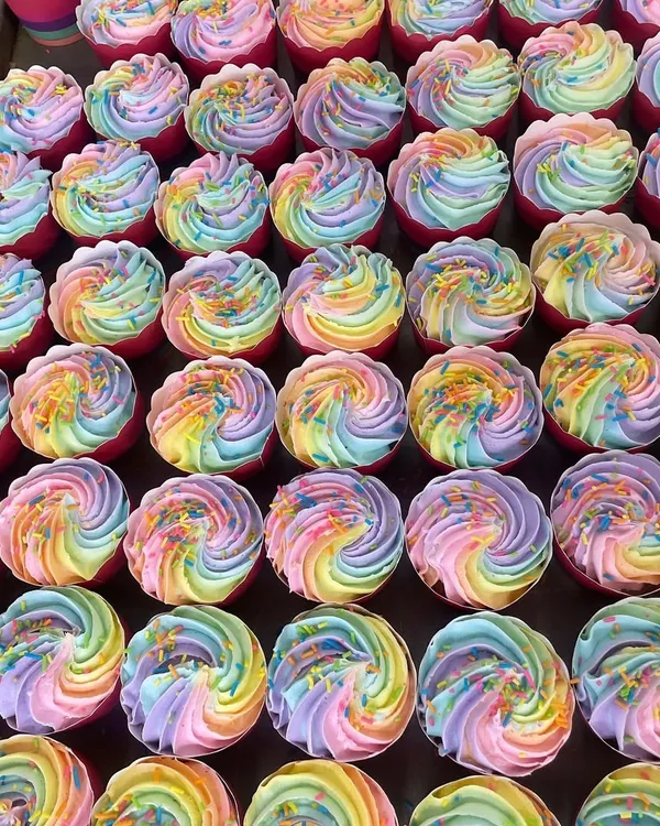 A full tray of our rainbow cupcakes ready for a corporate event. The swirl of pastel colors makes for a beautiful and delicious display.