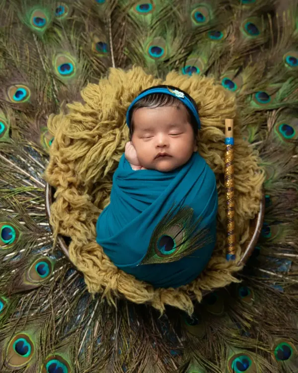 A classic Krishna-themed portrait, with your newborn swaddled peacefully against a backdrop of magnificent peacock feathers. I use a tiny flute prop and a matching headband to complete this divine look.