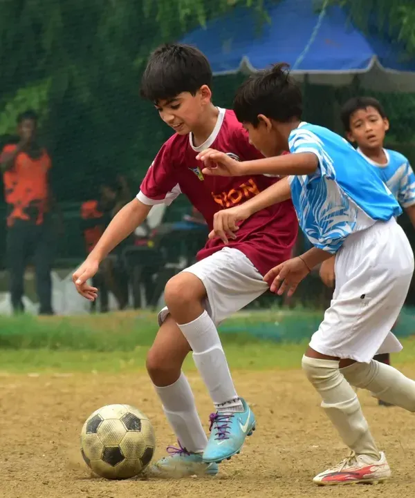 A player shields the ball from an opponent during a competitive match. This shows the strength and ball control we develop in our training sessions.
