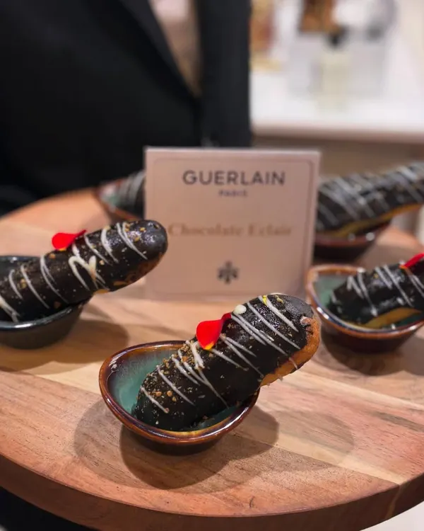 Decadent Chocolate Éclairs created for a luxury event. Each choux pastry is filled with cream and topped with a glossy chocolate glaze and a delicate edible flower.