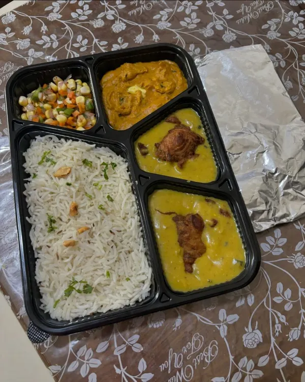 A classic North Indian meal box featuring Jeera Rice, creamy Paneer Butter Masala, Kadhi Pakoda, a fresh corn salad, and soft rotis packed separately to stay fresh.