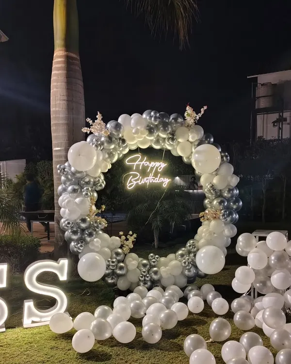 The combination of a 'Happy Birthday' neon sign and large, illuminated 'SS' initials makes this outdoor setup feel personal and look professional. These lighting elements are central to the design.