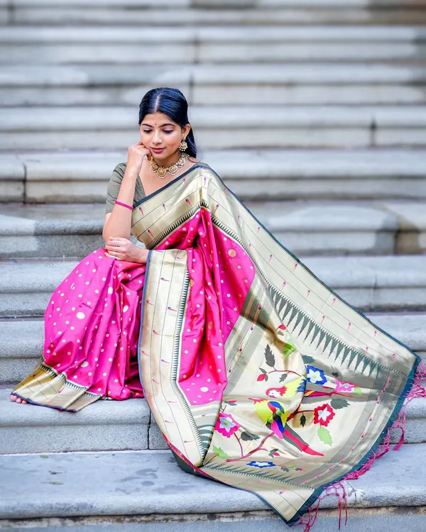This beautiful pink Paithani semi-soft silk saree features a stunning pallu with colorful parrot motifs. The way it drapes on the steps showcases the richness of the fabric and its intricate weave.