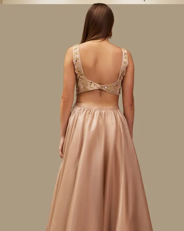 The back of this champagne gold lehenga shows off a beautifully detailed, hand-embroidered blouse. It's a timeless design that celebrates grace and elegance.