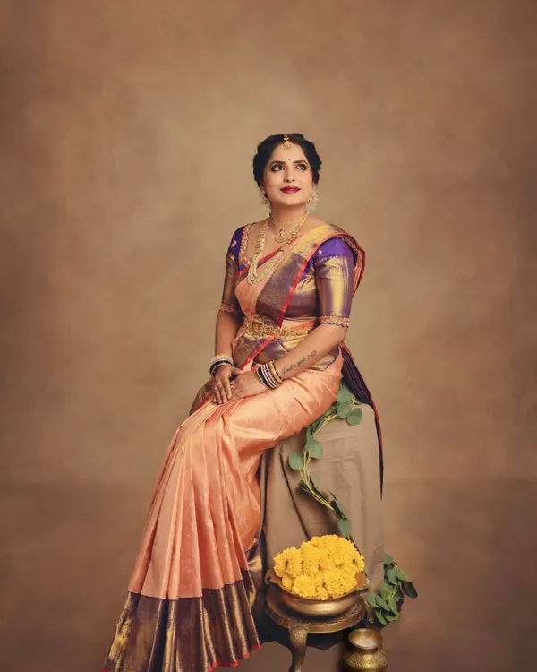 A beautiful seated pose that captures the regal feel of a traditional saree look. The composition is balanced with marigolds and greenery, adding a festive touch to this classic portrait.