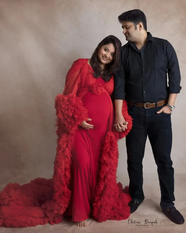 A classic couple's pose. Dressed in a stunning red gown, she holds hands with her partner, capturing the simple, powerful connection between them.