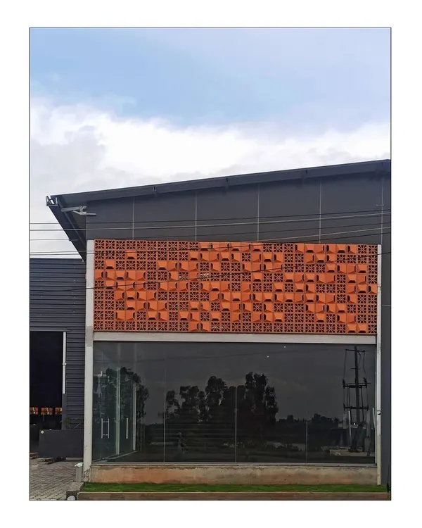 The terracotta jali facade at the Om Marble project combines a traditional material with a contemporary, randomized pattern. This creates a unique identity for the building while providing practical benefits like shading and ventilation.