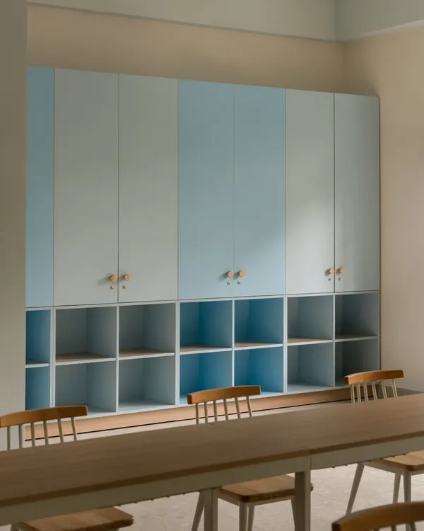 Custom storage solutions in one of the activity rooms. The combination of closed cabinets and open cubbies, finished in a calming two-tone blue, provides ample, organized space for materials.