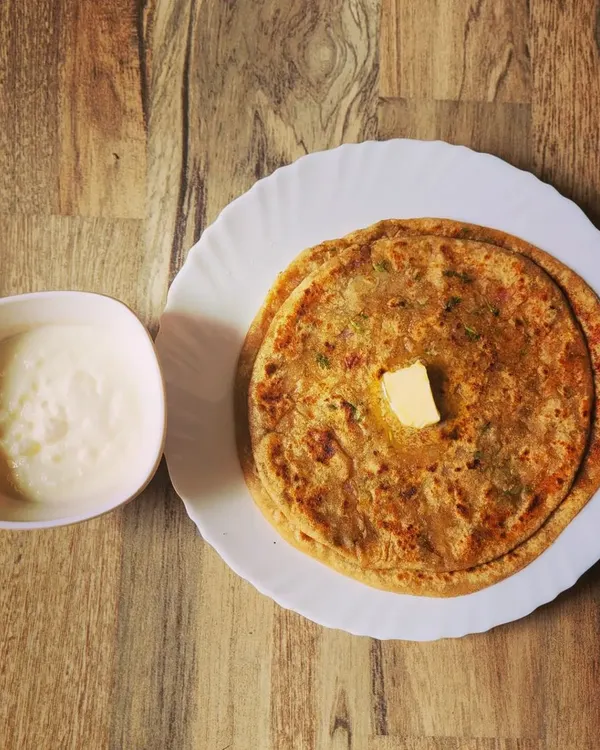 A classic Punjabi breakfast of Aloo Paratha. These fluffy flatbreads are stuffed with spiced potatoes, cooked until golden, and served with a dollop of butter and a side of cool dahi.