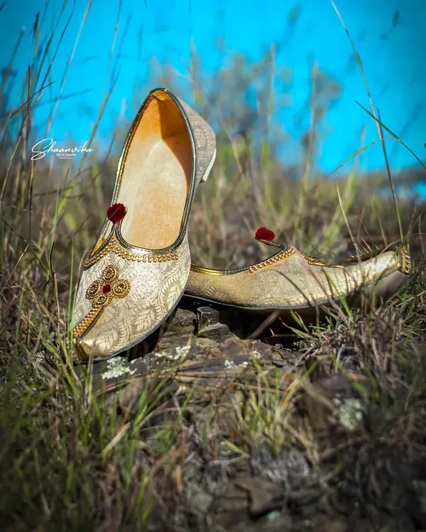 The groom's traditional shoes (jutti), placed in a natural, grassy setting. I believe in capturing every detail that completes the wedding look.