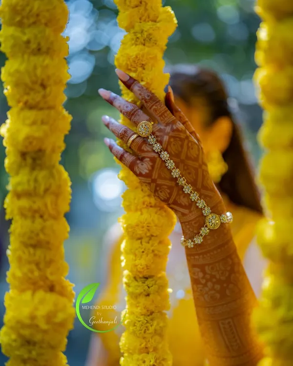 A beautiful, artistic shot of the bride's mehendi, with her hand elegantly placed among marigold flower strings.