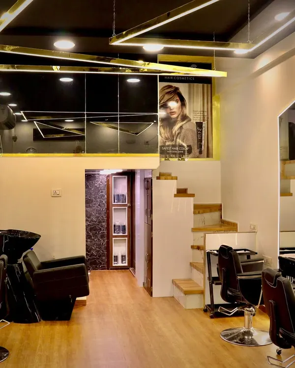 A look at our salon's stylish, multi-level interior. We've designed the space with modern gold lighting fixtures, sleek black accents, and comfortable styling stations to create a high-end, professional atmosphere.