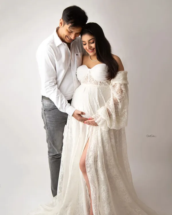 A beautiful, tender moment between parents-to-be. They are both dressed in white, creating a light and airy feel for this classic couple's maternity portrait.