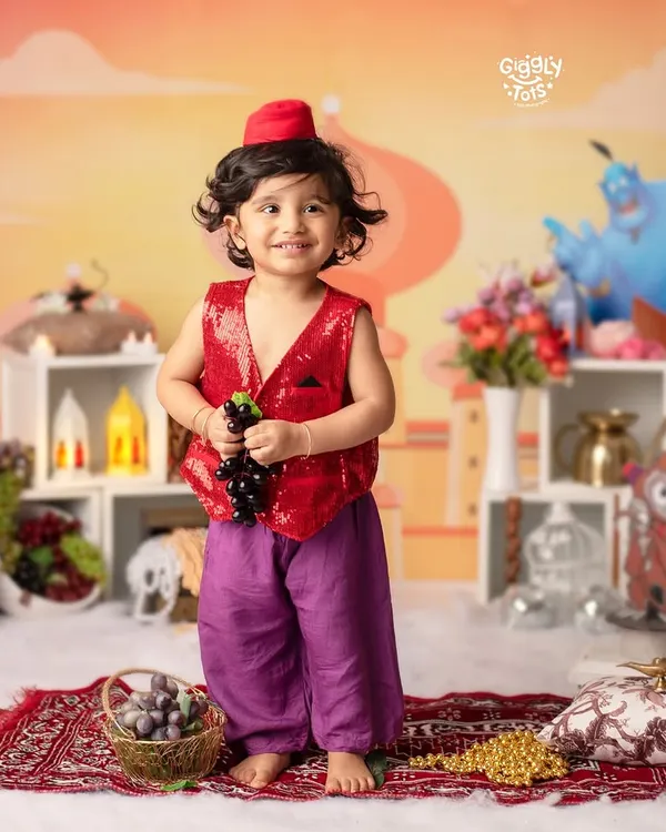 Experience the enchantment of Aladdin's world. This little one, dressed in a sequined vest and fez, is ready for a magical adventure.